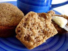 two muffins on a blue plate next to a cup of coffee and butter