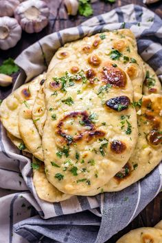 some food is sitting on a cloth in a bowl and next to garlic, parsley and mushrooms