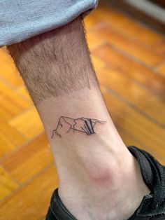 a man's foot with a small tattoo of a cow on the side of his leg