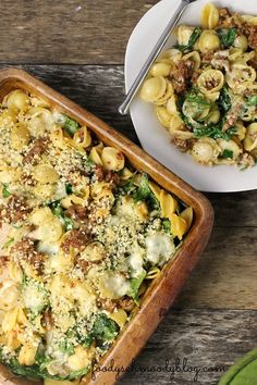 a casserole dish with pasta and spinach is on the table next to a bowl of broccoli