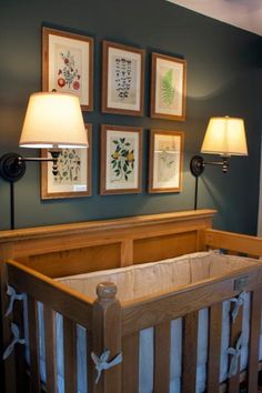 a baby's crib with pictures on the wall above it and two lamps