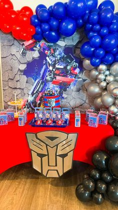 a table topped with balloons next to a giant robot balloon arch and an autographed wall