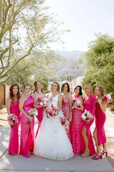 a group of women standing next to each other wearing pink dresses and holding bouquets