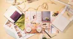 a table topped with papers and flowers on top of a wooden table next to scissors