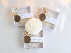 three wedding favors in small boxes with flowers and wax seals on the top one is for each guest