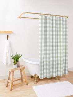 a blue and white plaid shower curtain next to a wooden stool with a potted plant on it