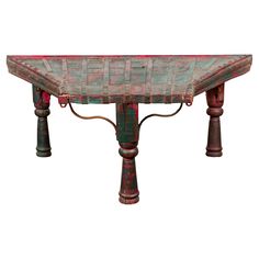 an old wooden table with red and green paint on the top, sitting against a white background