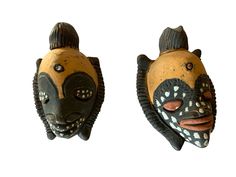 two african masks with different designs on them, one is brown and the other is black