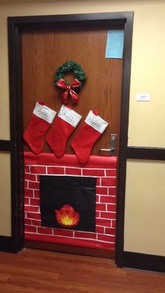 the door is decorated with stockings and wreaths on top of a brick fire place