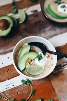 a bowl filled with chicken and avocado on top of a wooden table