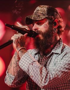 a bearded man with tattoos on his face and beard, holding a microphone up to his mouth