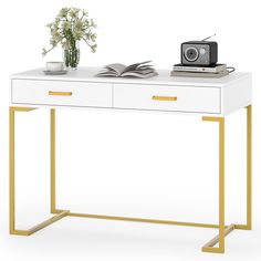 a white desk with gold legs and a book on it, next to a camera