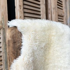 a white sheepskin rug sitting on the side of a wooden building with shutters