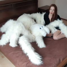 a woman sitting on top of a bed covered in giant white furry animal arms and legs