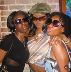 three women are posing for the camera in front of a brick wall and wearing sunglasses