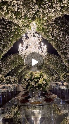 an elaborate table with flowers and chandelier hanging from the ceiling in front of it