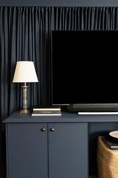 a flat screen tv sitting on top of a blue cabinet in a living room next to a lamp