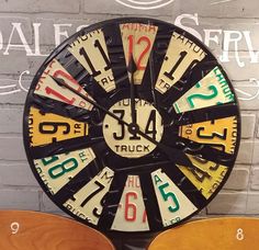 a clock made out of license plates on a wall next to a chair and table