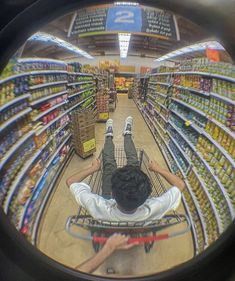 a man laying on top of a shopping cart in a grocery store surrounded by shelves