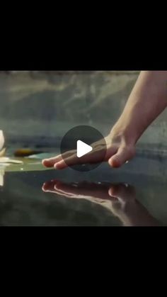 a person holding an object in their hand while standing next to the water with it's reflection