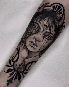 a black and white tattoo with a woman's face on her arm, surrounded by horns