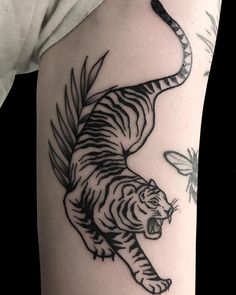 a black and white tiger tattoo on the right thigh, with a butterfly in the background