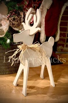 a wooden reindeer sitting next to a christmas tree