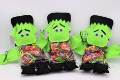 three green stuffed toys with candy in their hands and one is wearing a black hat