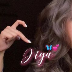 a woman with long grey hair pointing to the word diya on her fingernail