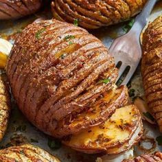 baked potatoes with herbs and seasoning on top, next to a knife and fork