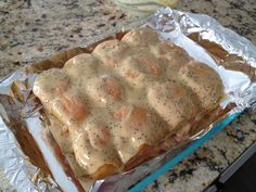 a sandwich covered in sauce sitting on top of aluminum foil next to a glass container