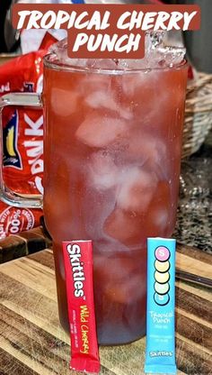 a drink and some candy are on a wooden table with a sign that says tropical cherry punch