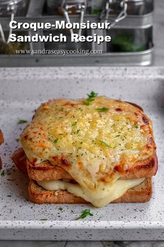 a close up of a sandwich on a plate with cheese and herbs in the background