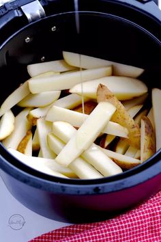 an open crock pot filled with sliced apples on top of a red and white checkered table cloth