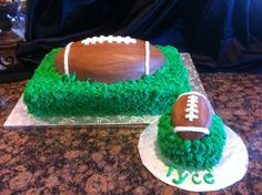 a football cake with green frosting and grass on the top is sitting on a table