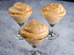 three glasses filled with dessert sitting on top of a table