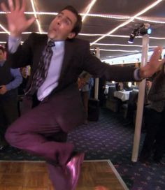 a man in a suit and tie jumping on a dance floor