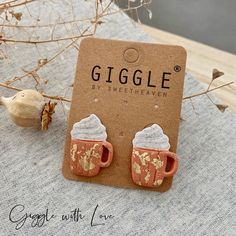 a pair of cupcake earrings sitting on top of a table next to some dried flowers