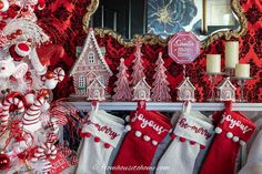 christmas stockings are hanging on the mantle in front of a red and white tree with candy canes