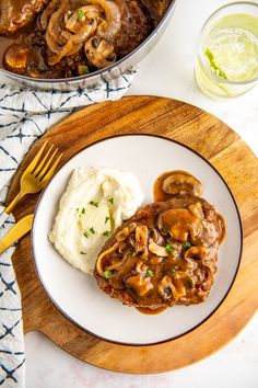 a white plate topped with mashed potatoes and meat covered in mushroom gravy