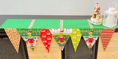 a green table topped with a cake and bunting banner next to a small christmas tree