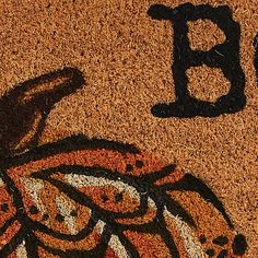 the word b is written in black and orange on a door mat with an image of a bird