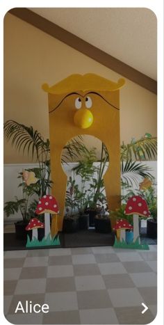 a large yellow clock sitting in the middle of a room next to potted plants