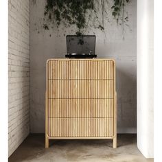 a wooden dresser sitting next to a brick wall with a laptop on top of it