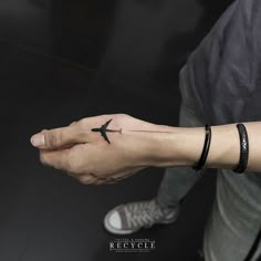 a person with a small tattoo on their left hand holding an airplane in the air