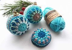 three crocheted balls of yarn next to a pine branch