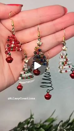 a hand holding three christmas tree earrings in it's palm with pine cones and beads