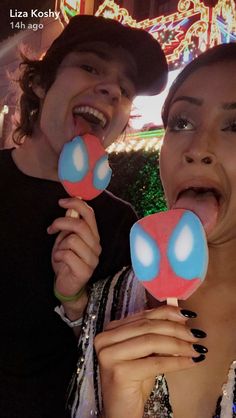 two people holding lollipops in their mouths