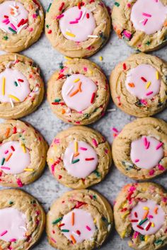 cookies with sprinkles and pink frosting are arranged on a baking sheet