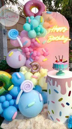 there are many balloons and decorations on the ground outside in front of a birthday sign